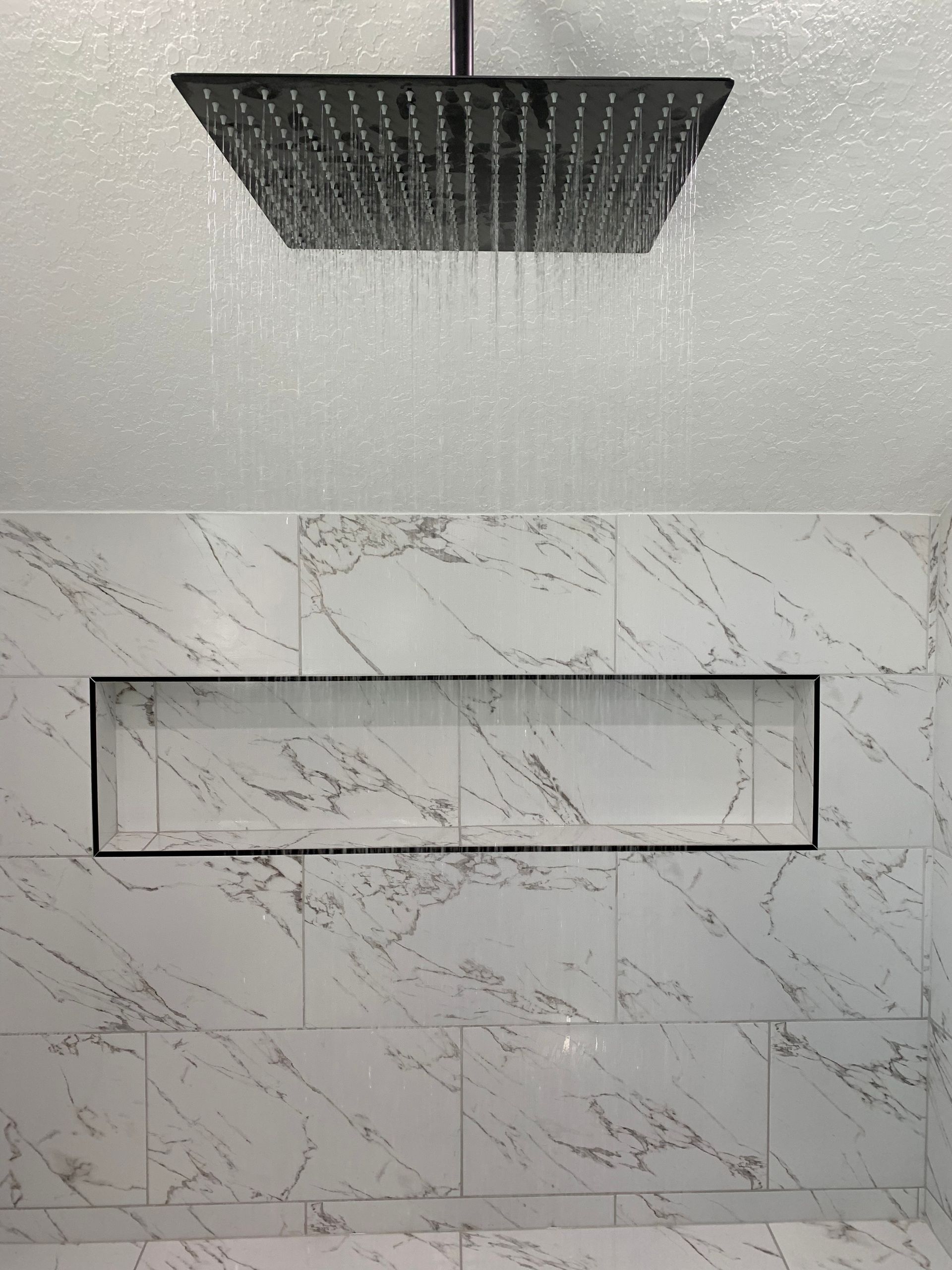 A shower head is hanging from the ceiling in a bathroom.