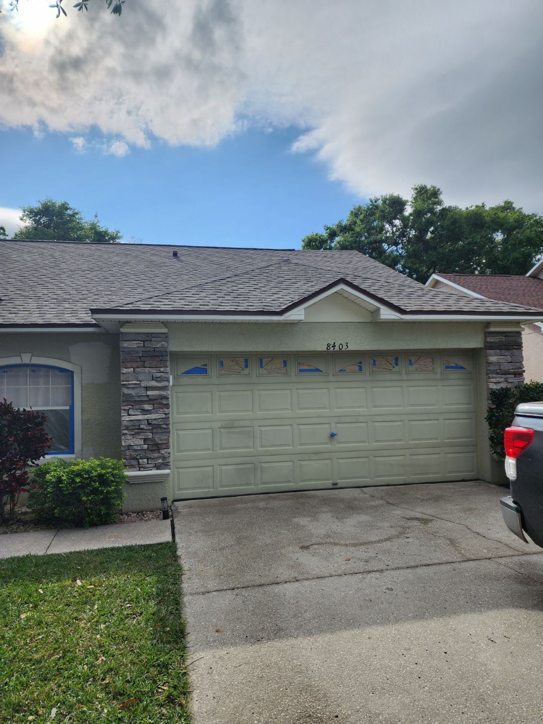 A car is parked in front of a house with a garage door.
