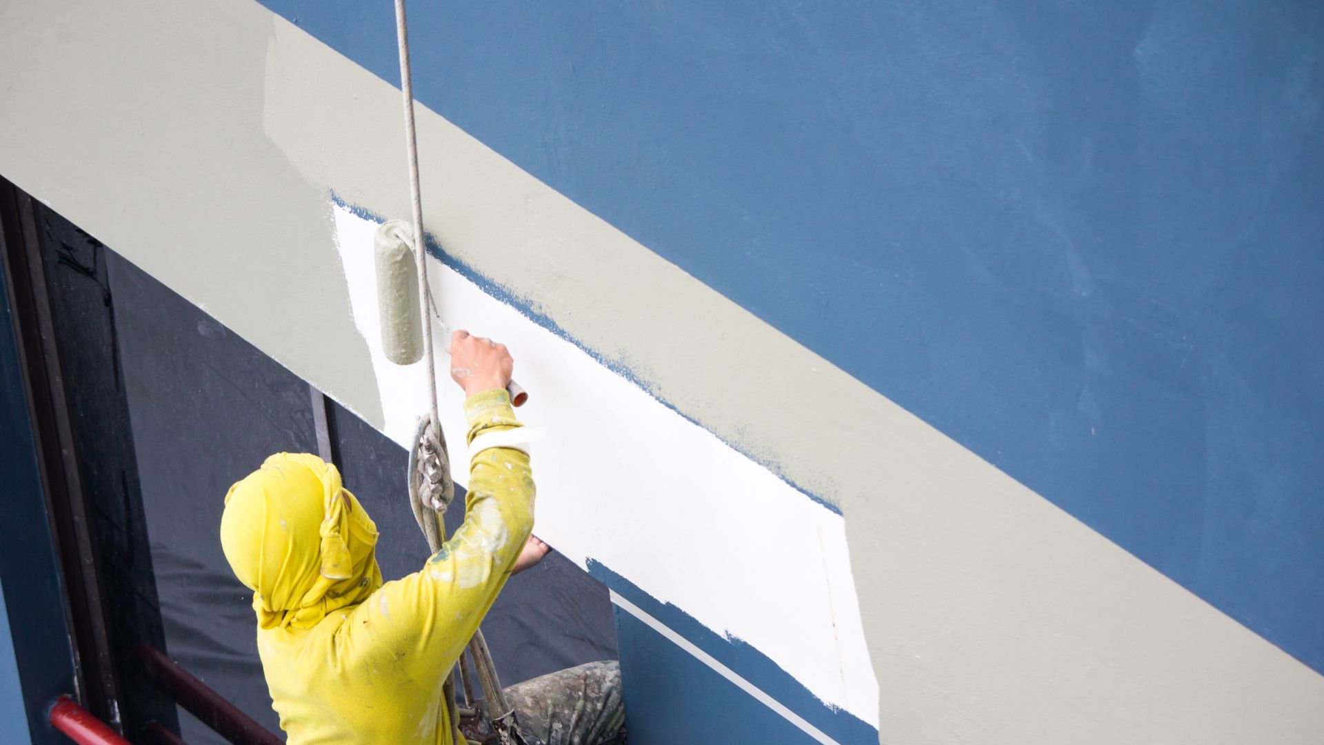 A person is painting a wall with a roller.