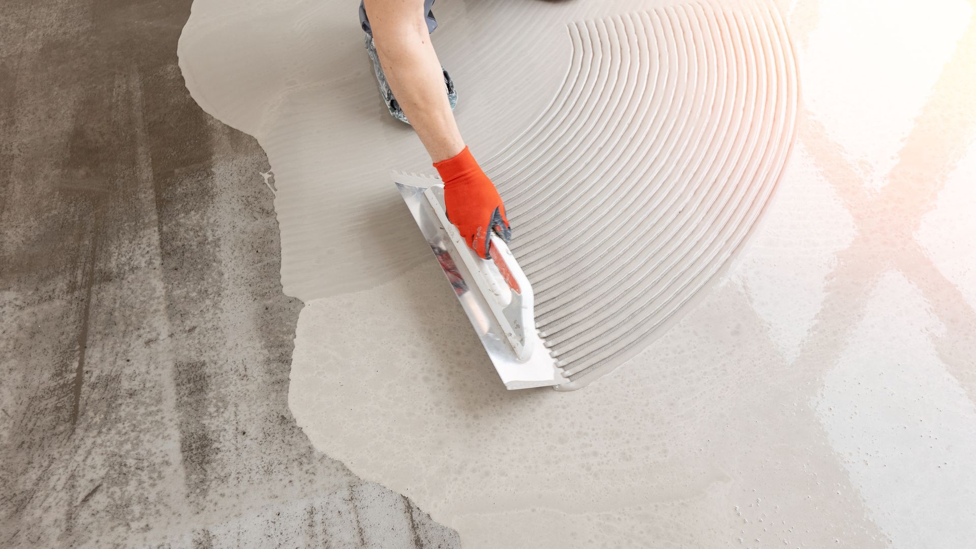 A person is spreading a concrete floor with a trowel.