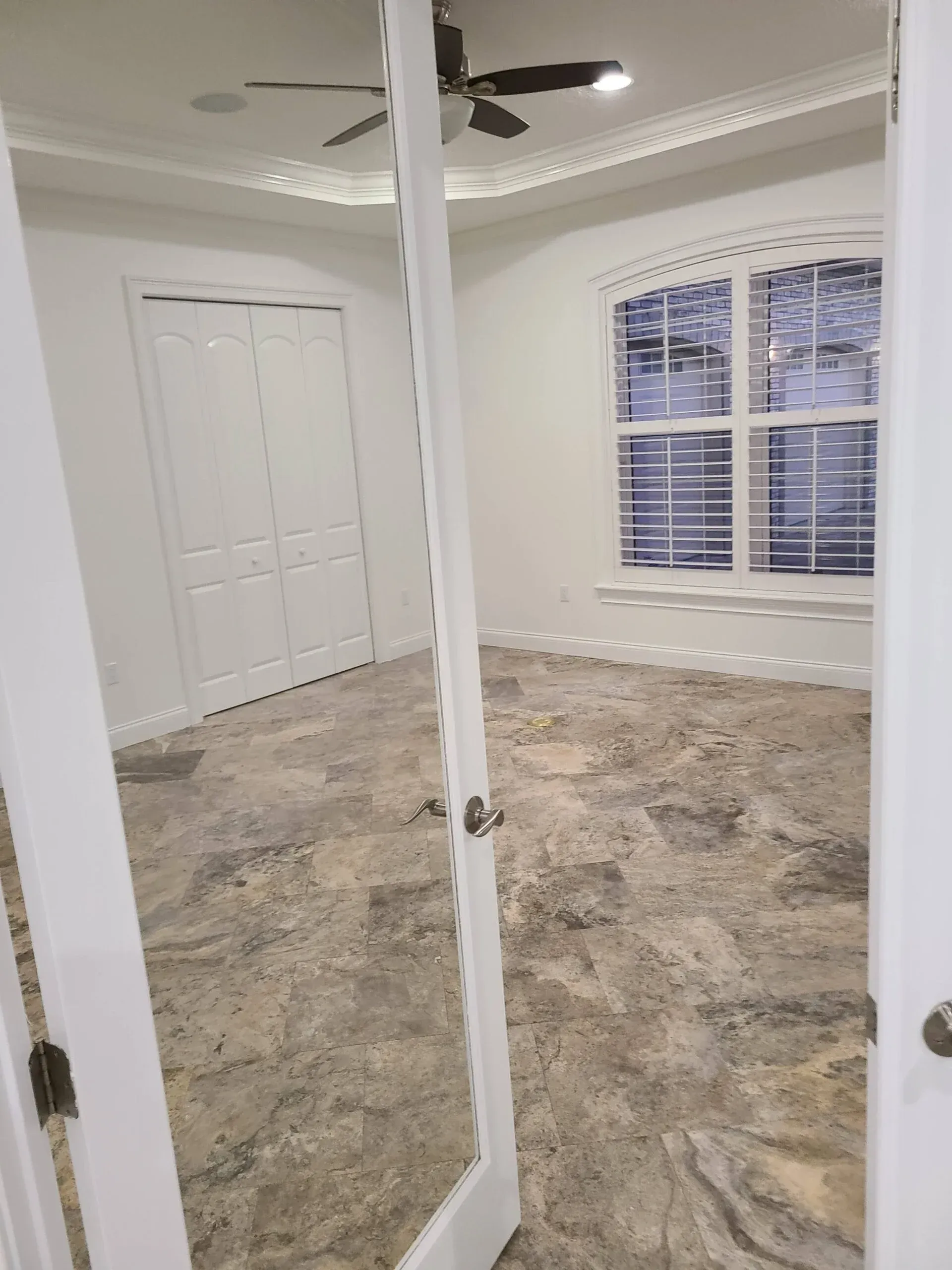 A bedroom with a ceiling fan and a mirror on the door.