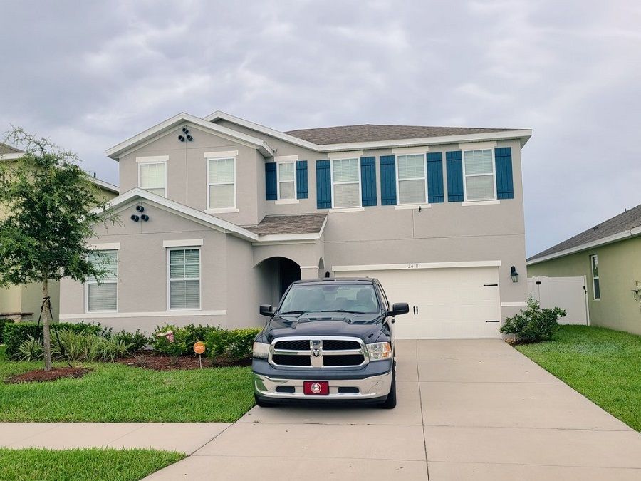 A dodge truck is parked in front of a large house.