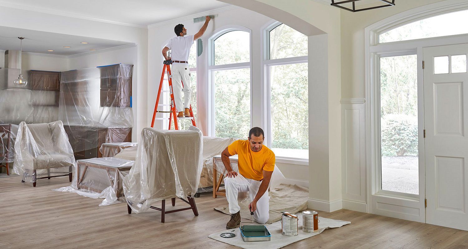 Two men are painting a living room in a house.