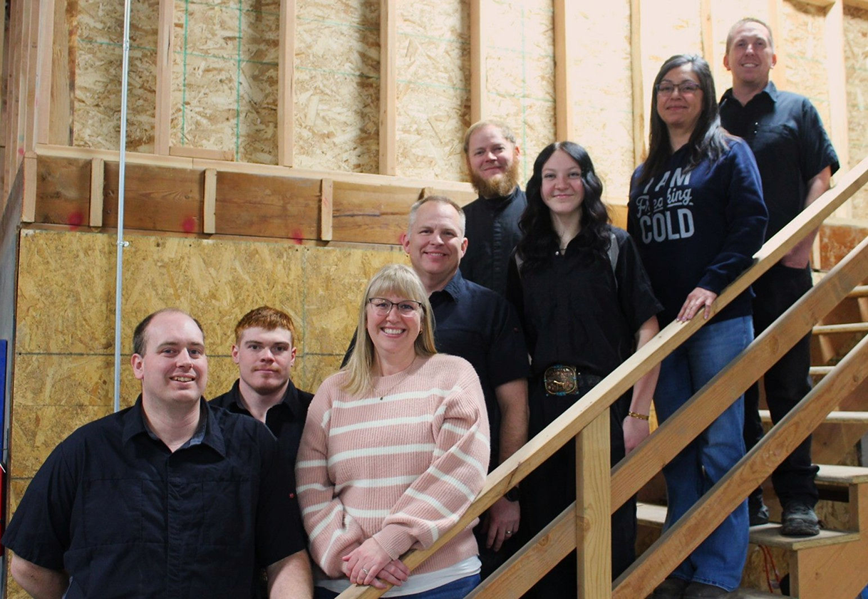Group of people on wooden stairs in a partially finished building, smiling at the camera | Don's Repair