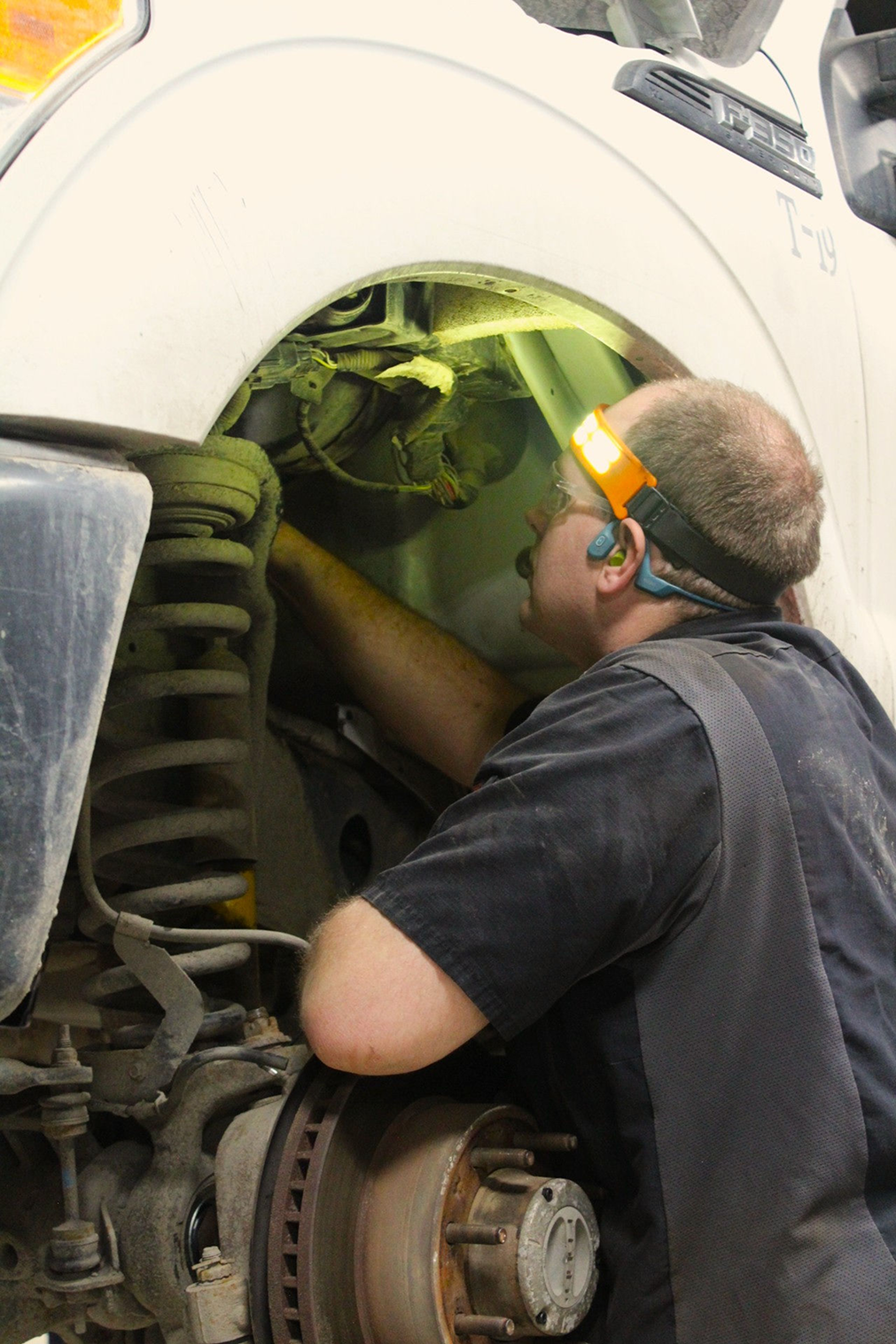 Mechanic working on a car wheel, wearing a headlamp | Don's Repair