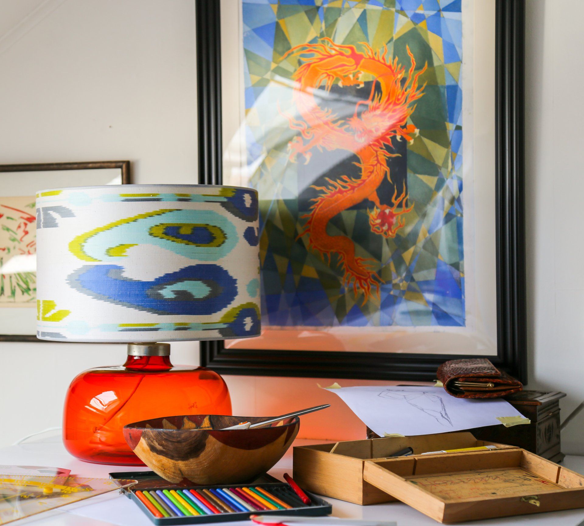 Oranje lamp, drakenkunst en knutselspullen op een witte tafel.