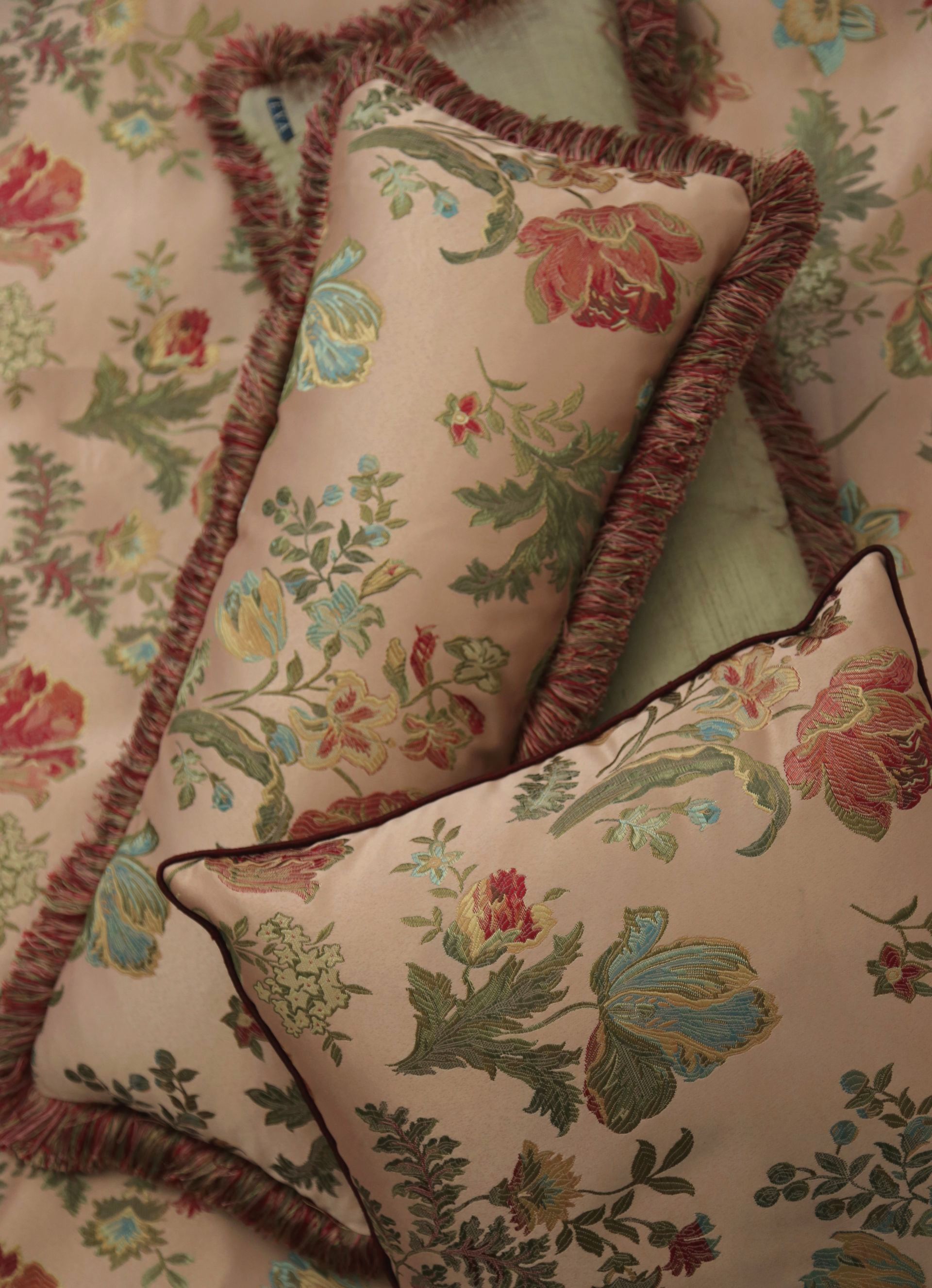 Sierkussens van Italiaans jacquard met franjes aan de randen, op een bed gelegd.