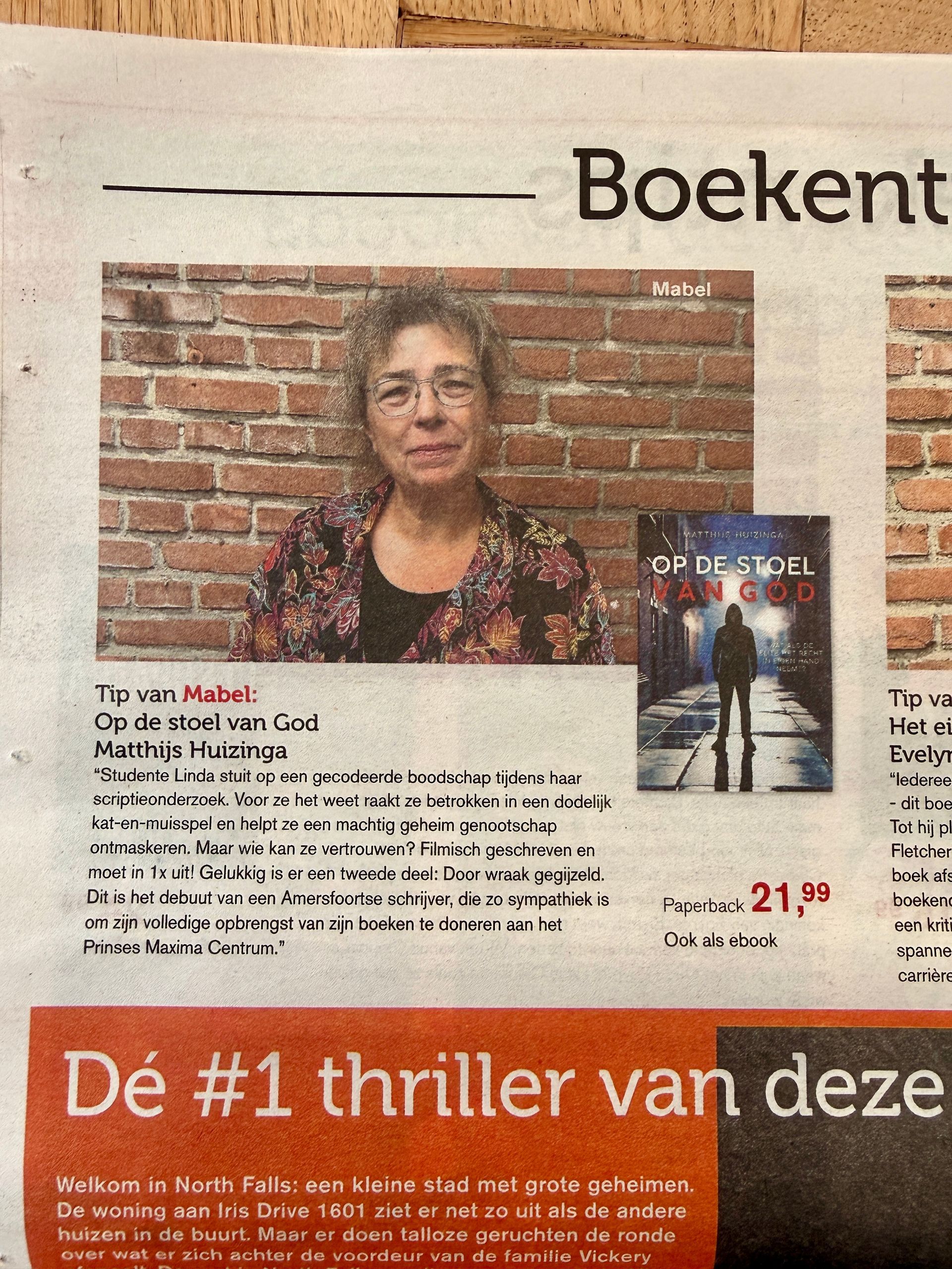 Tijdschriftpagina met een vrouw voor een bakstenen muur en de omslag van een thrillerboek, met Nederlandse tekst.