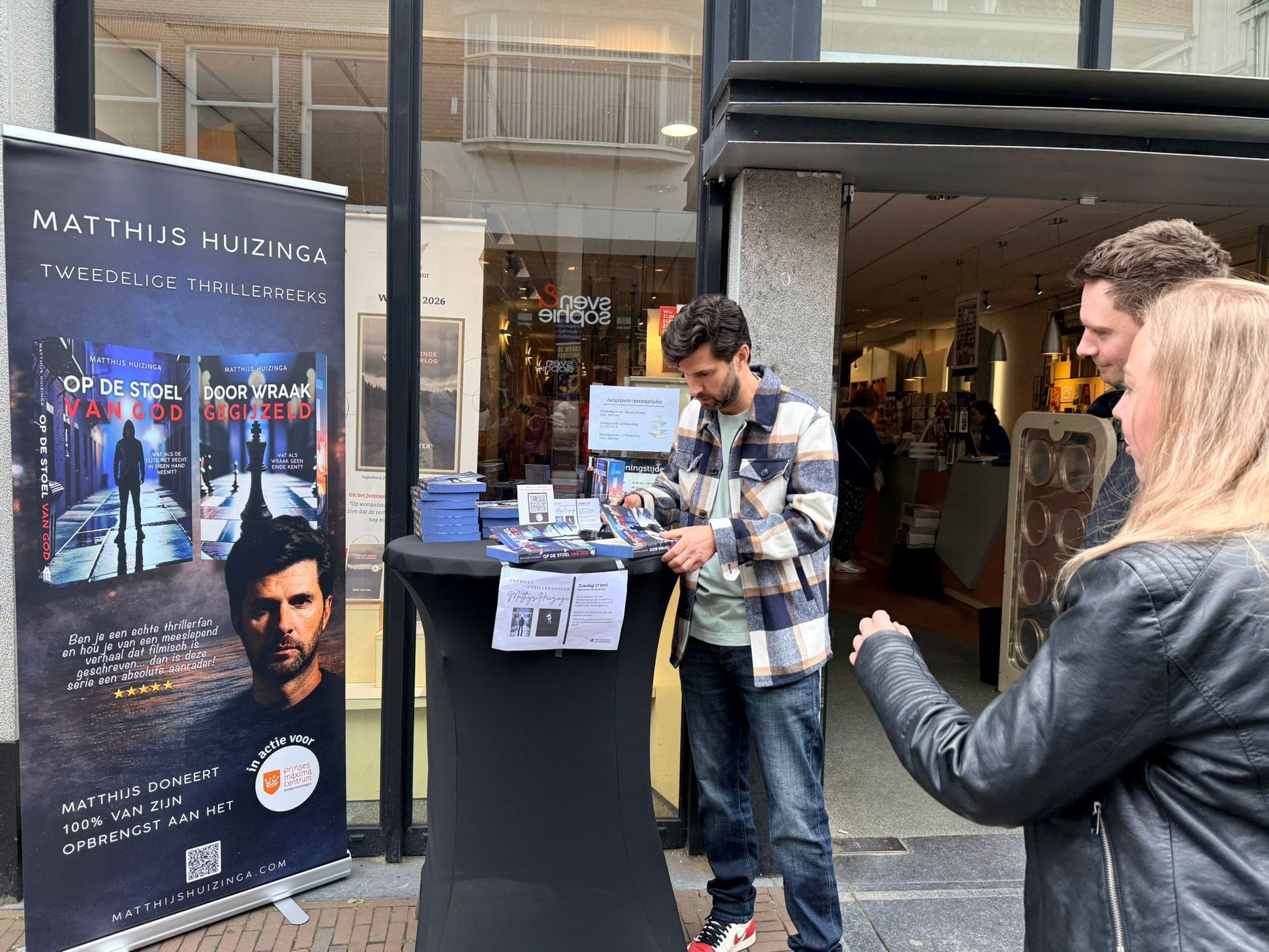 Mensen bekijken een vitrine met filmposters bij een kiosk in de openlucht.
