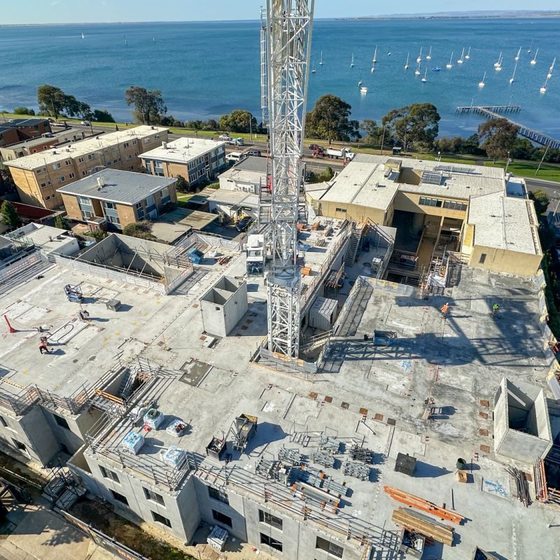 Construction site with crane overlooking buildings and waterfront.