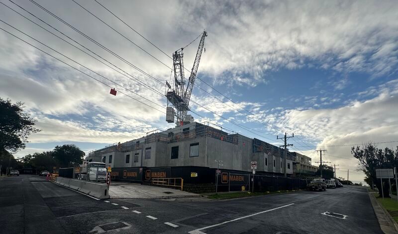 Construction site with a crane, building under construction, overcast sky.