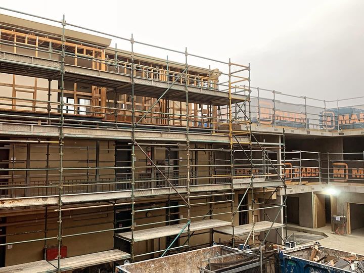 Building under construction with scaffolding. Gray sky, wooden frames, metal scaffolding.