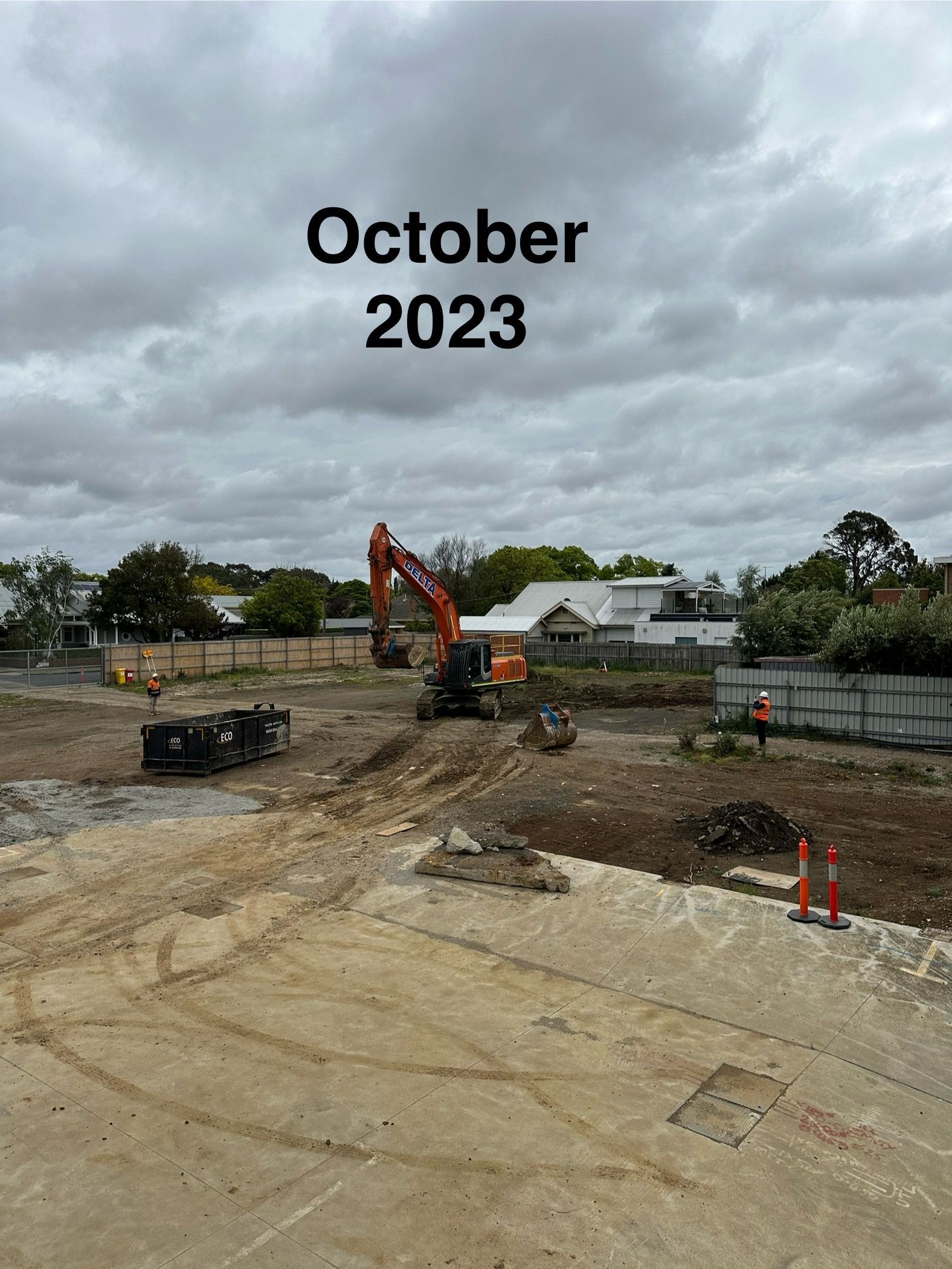 Construction site with an orange excavator under cloudy skies in October 2023.