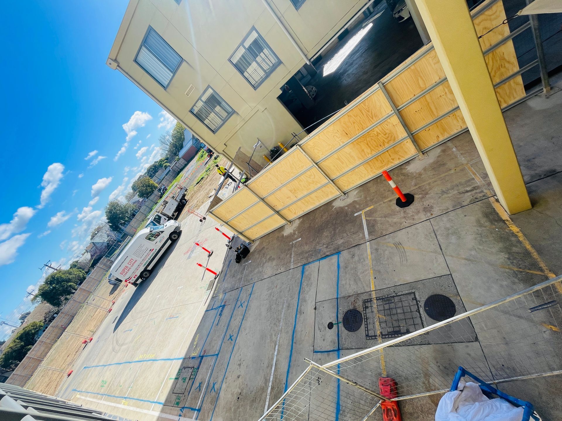 Construction site with wooden barriers, a truck, and blue painted markings on the ground.