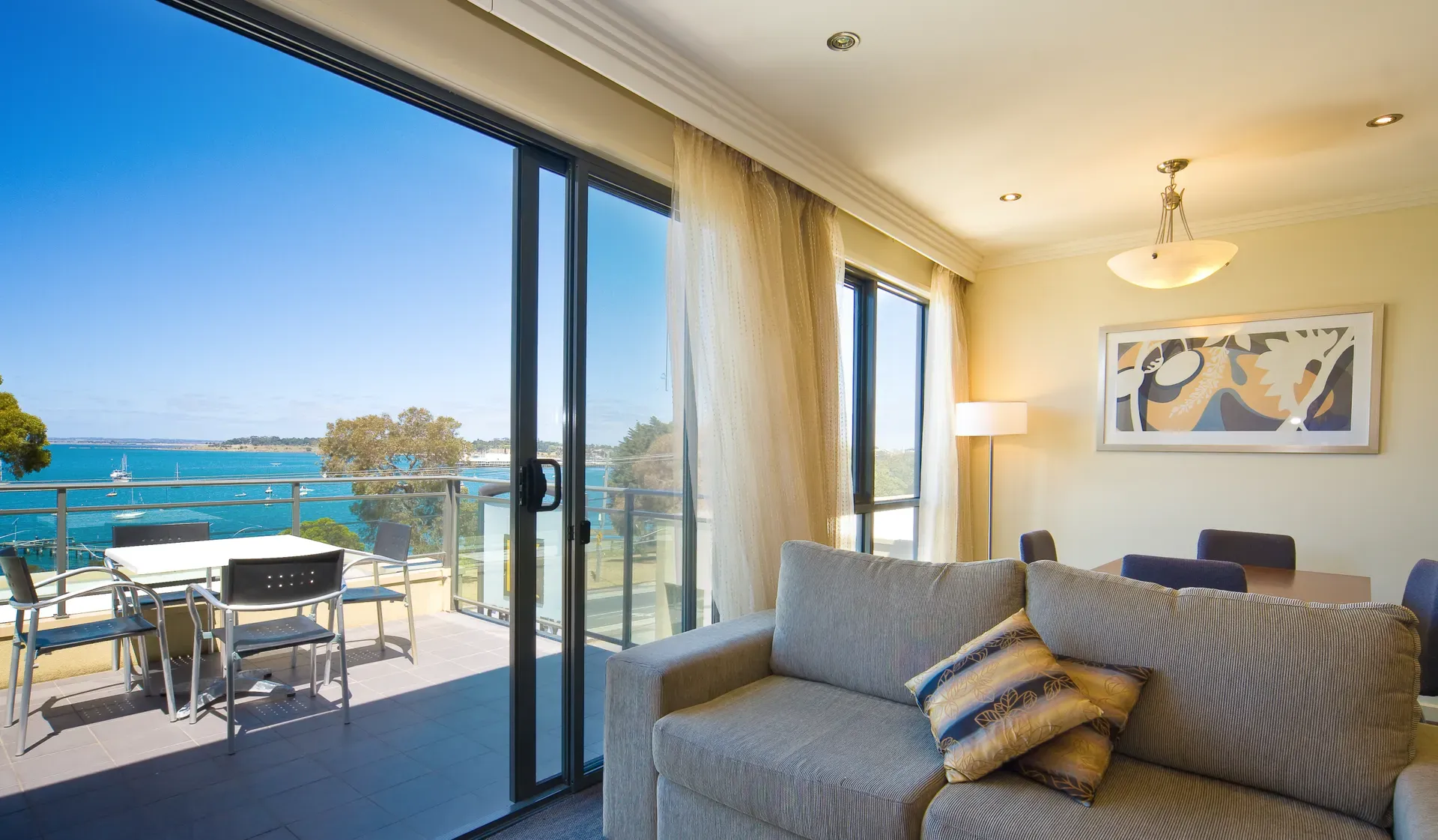 Living room with sliding glass doors opening to a waterfront view and balcony with outdoor seating.