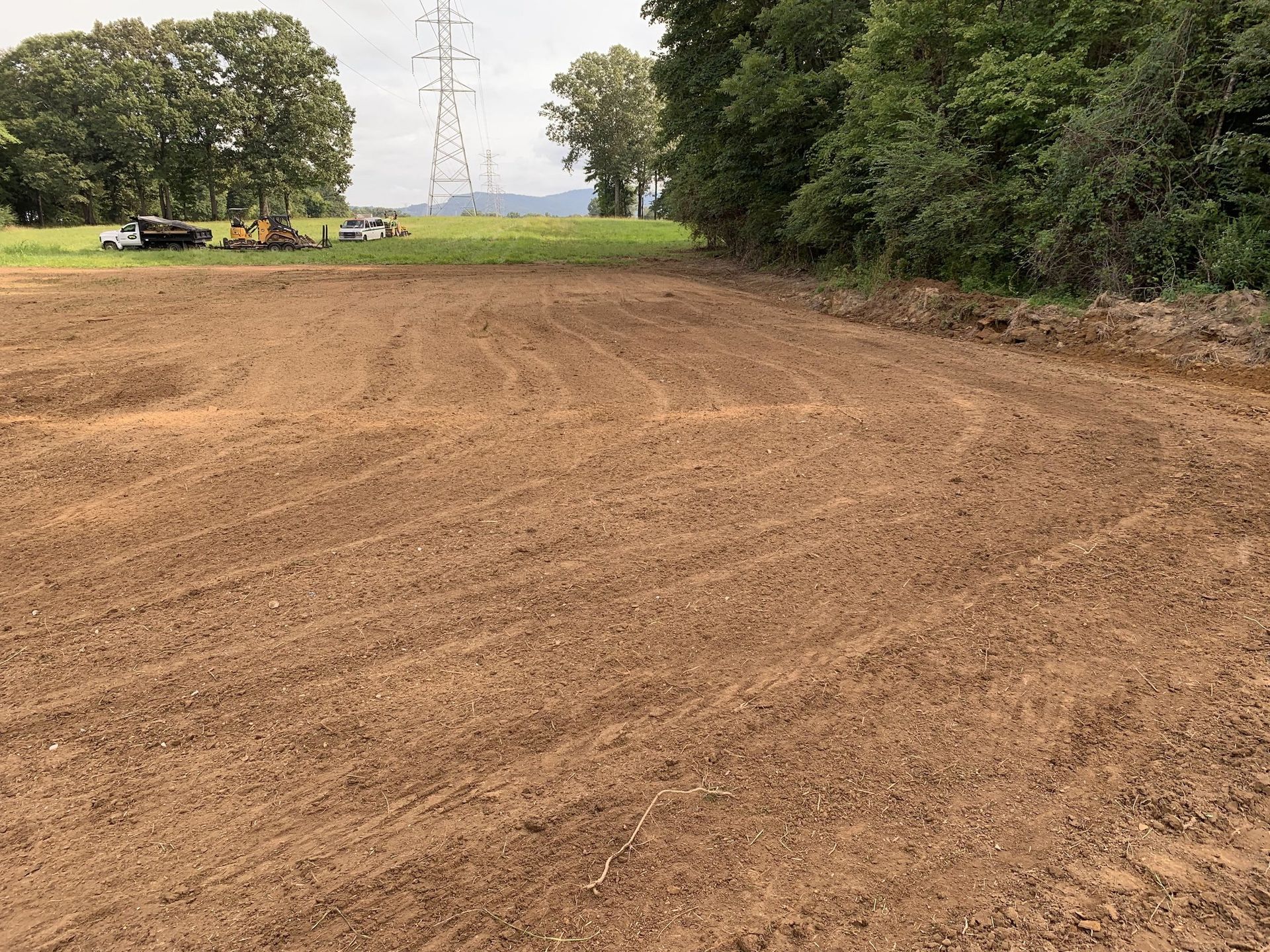 Two bulldozers are parked next to each other in a dirt field.