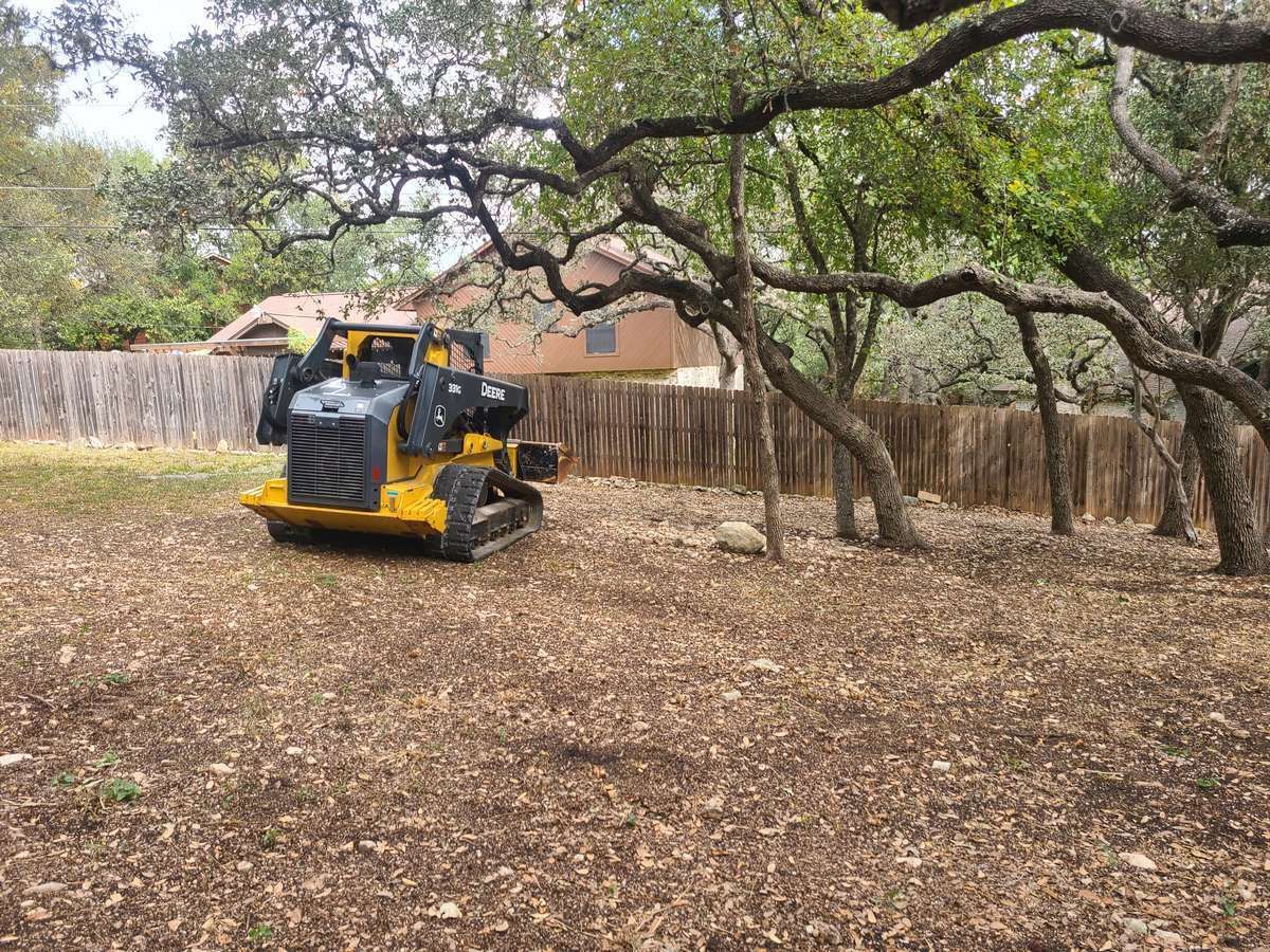 Yellow trackloader mulching on a residential property in Georgetown, TX.