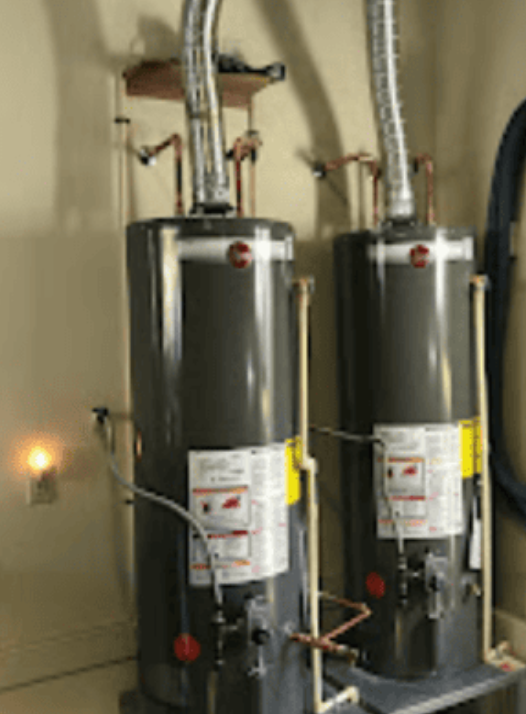 Two tall, grey residential water heaters stand side-by-side with silver exhaust vents connected to the ceiling.