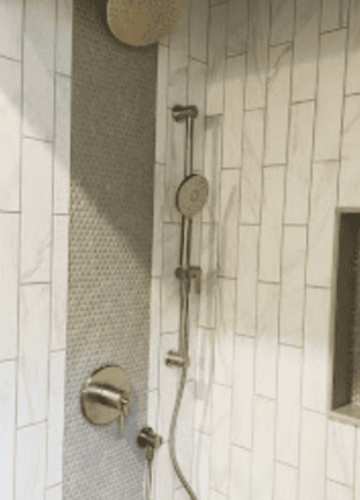 A shower interior with a gray mosaic tile accent wall, white subway tiles, and brushed nickel hardware.