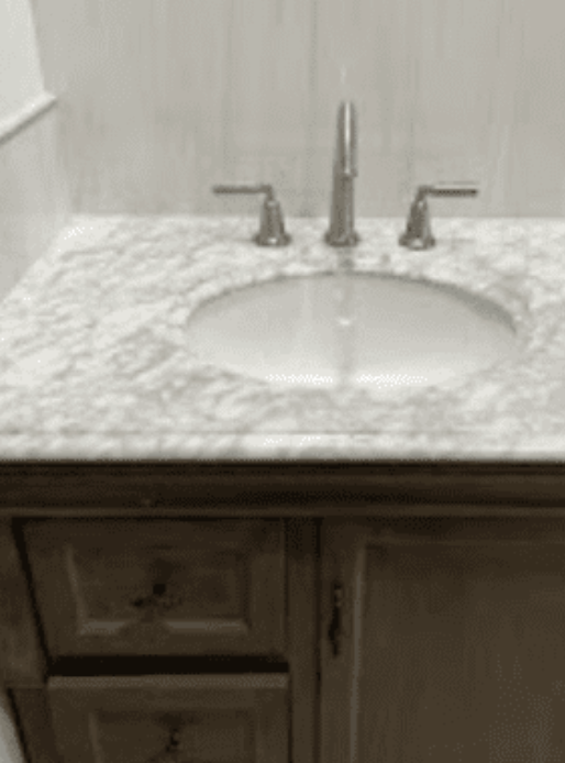 A bathroom vanity with a white marble countertop, an oval undermount sink, and a modern metal faucet.