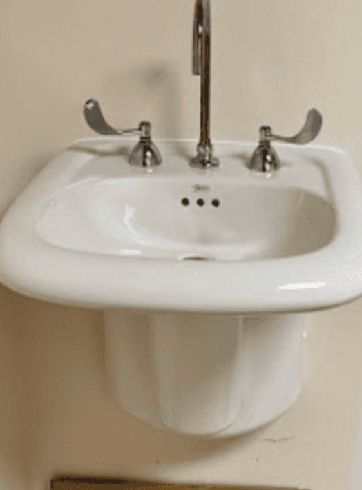 A white wall-mounted bathroom sink featuring a chrome faucet with two long, easy-to-operate medical-style lever handles.