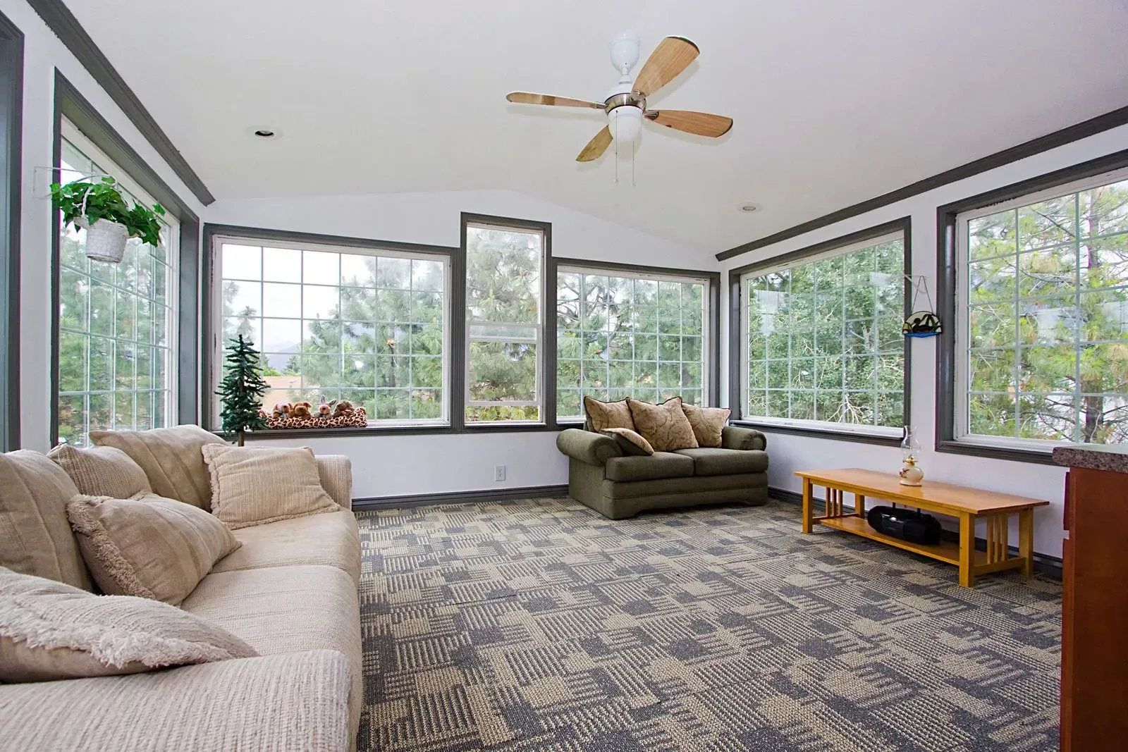 A living room with a lot of windows and a ceiling fan