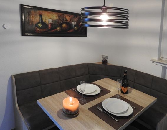 Cozy dining nook with booth seating, table set for two, lit candle, and art on the wall.
