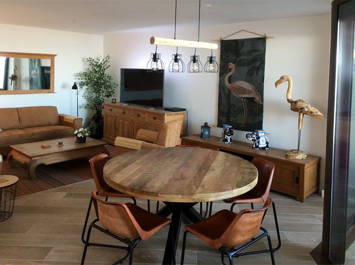Living room with wooden furniture, round dining table, and flamingo art.