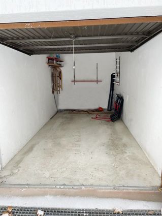 Empty garage interior with concrete floor and tools hanging on the walls.