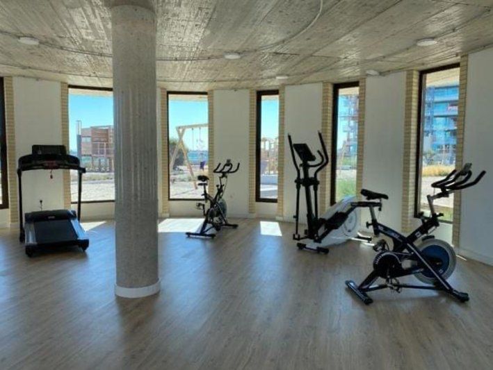 Gym with exercise machines and windows looking outside.