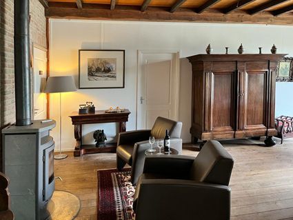 Cozy living room with fireplace, armchairs, and antique wooden cabinet.