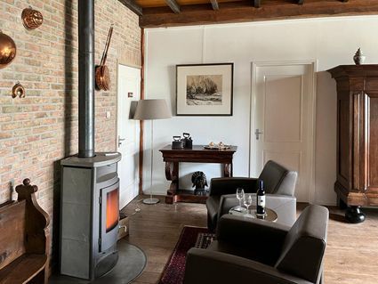 Cozy living room with brick wall, fireplace, armchairs, and antique furniture.