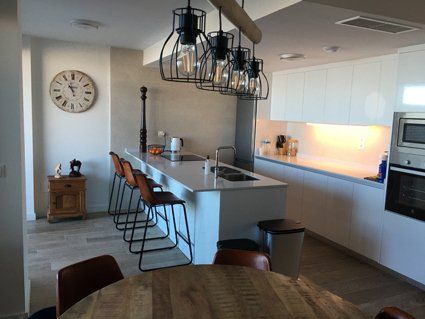 Modern kitchen with island, pendant lights, bar stools, and white cabinetry.