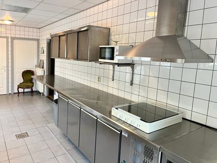 Commercial kitchen with stainless steel appliances, white tiled walls, and a microwave.