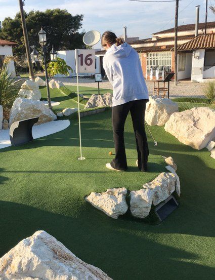 Person putting a golf ball on a miniature golf course; hole number 16.