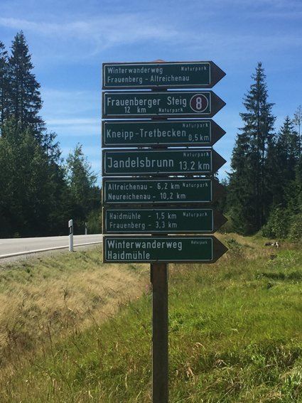 Signpost with green signs indicates hiking trails, distances in kilometers.