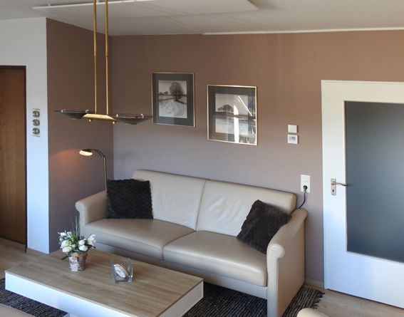 Living room with beige sofa, brown walls, art, and a coffee table.