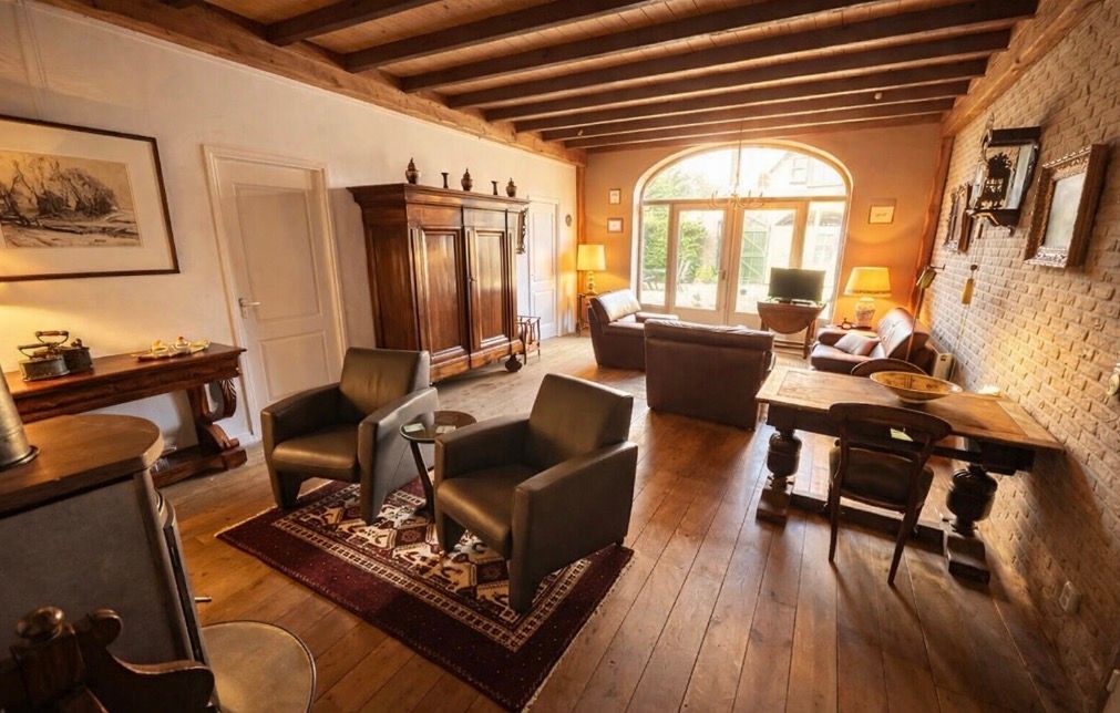 Living room with leather armchairs, wooden floors, and a large window.