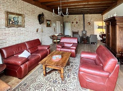 Living room with red leather furniture, exposed brick wall, and a wooden ceiling.