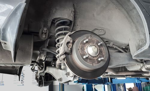 Close-up of a car’s disk brake inside a compartment, while being serviced in a repair shop. — Geelong VIC