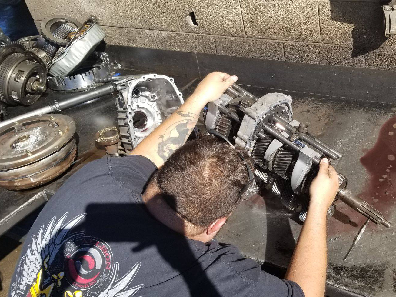 A man with a tattoo on his arm is working on a gearbox