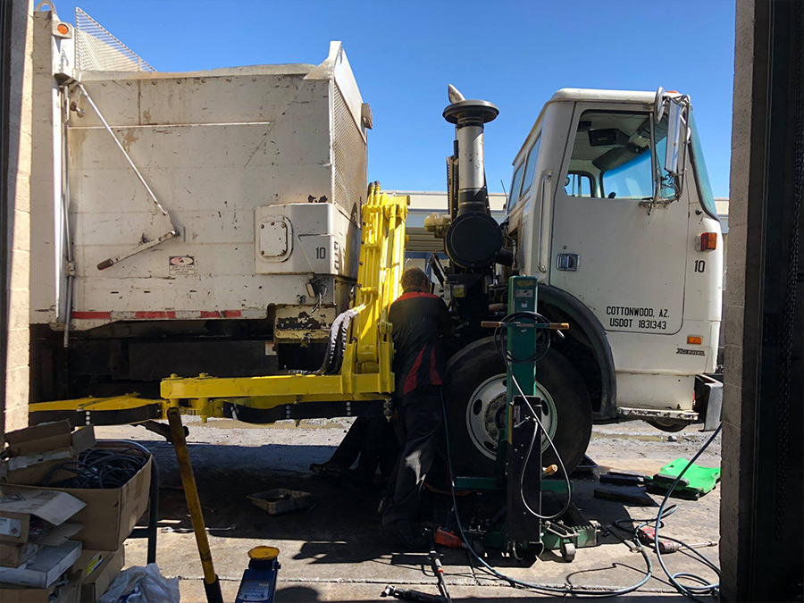 A man is working on a garbage truck in a garage.