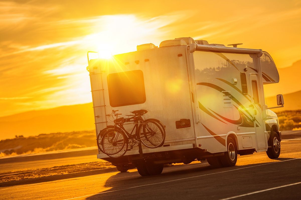 A rv is parked on the side of the road at sunset.
