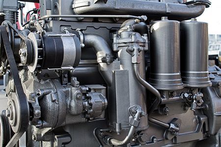 Gray industrial diesel engine with belts, pipes, and filters.