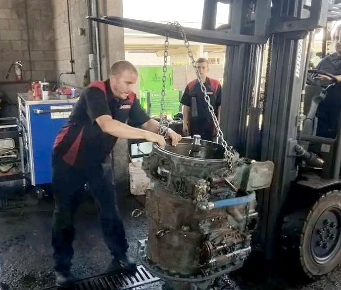 A man is working on a forklift in a garage.