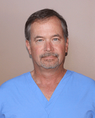 A man with a beard is wearing a blue scrub top.