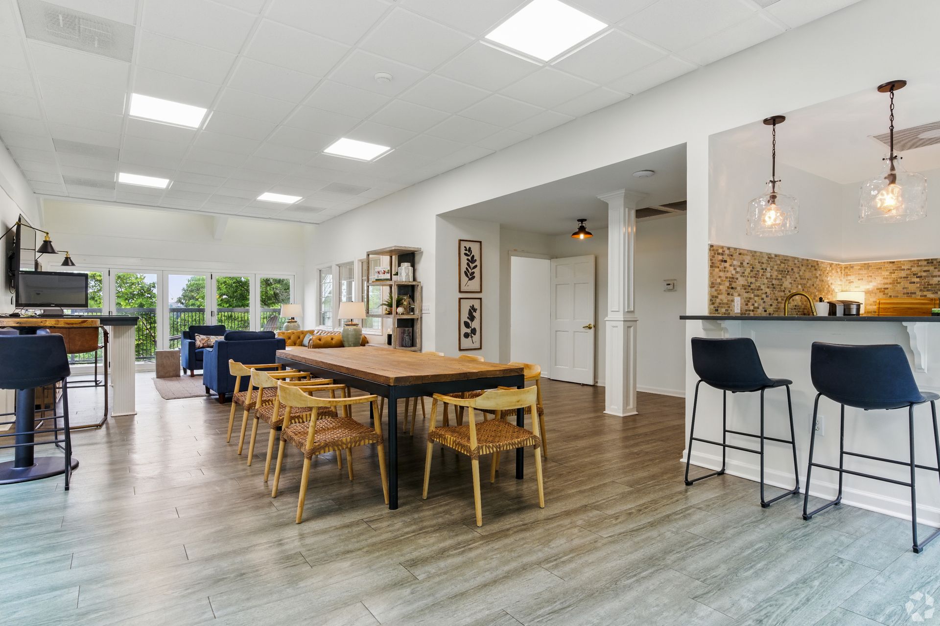 Spacious room with a large wooden table, bar stools, and open kitchen area.