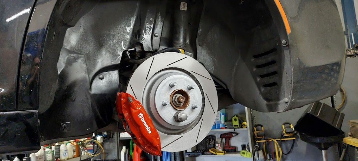 A Car With A Red Brake Caliper Is Sitting On A Lift In A Garage — Albion Park Auto Electrical & Mechanical In Albion Park Rail, NSW
