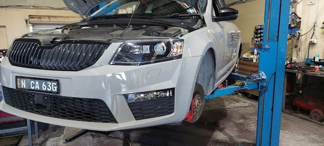 A White Car Is Sitting On Top Of A Blue Lift In A Garage — Albion Park Auto Electrical & Mechanical In Albion Park Rail, NSW
