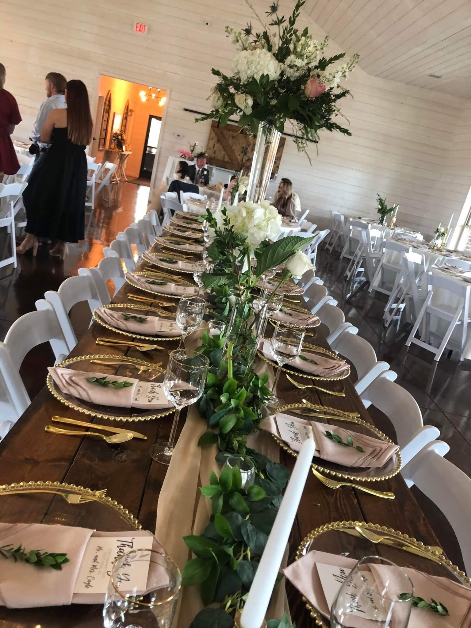 A long wooden table with plates , candles , and flowers on it.